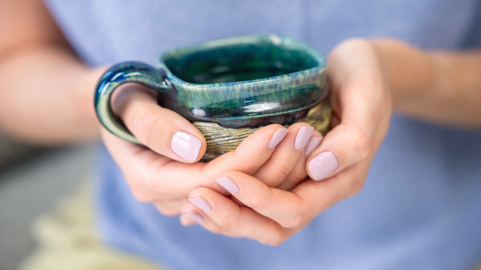 Hands cradling a handmade ceramic mug