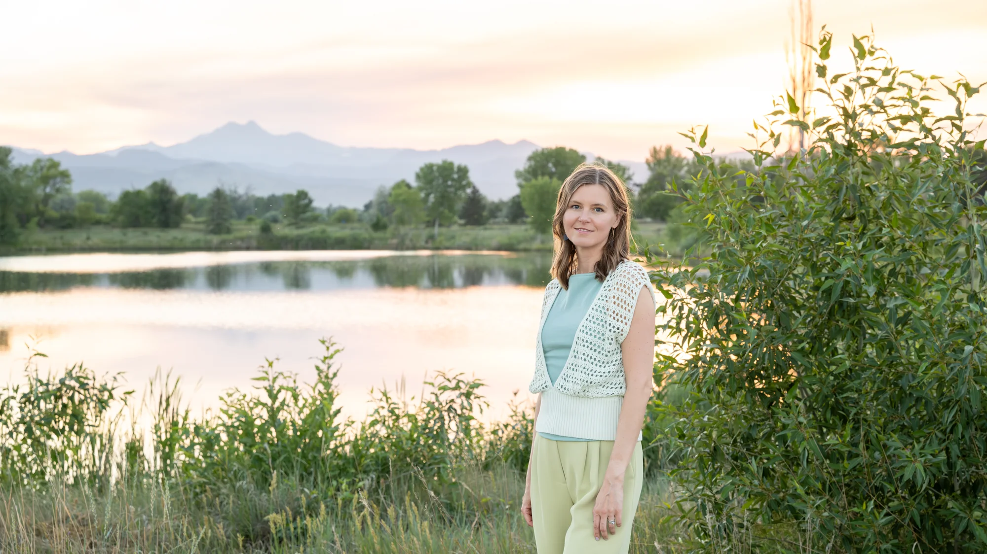 Anna by a lake at sunset, the Colorado Front Range behind her